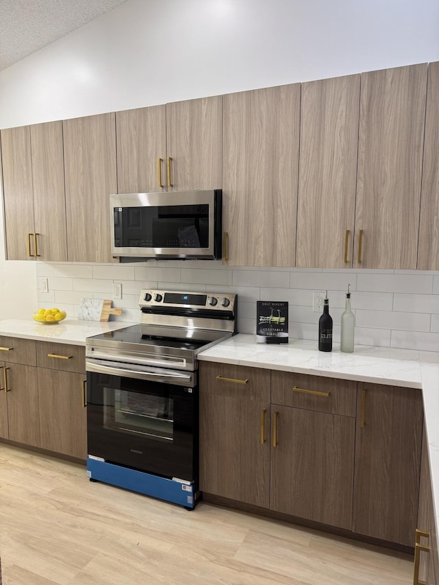 6092 Caladium Rd, Delray Beach, FL 33484 - kitchen featuring appliances with stainless steel finishes, backsplash, light wood finished floors, and light stone counters