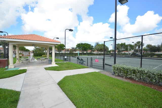 view of tennis court featuring a lawn, a gazebo, and fence