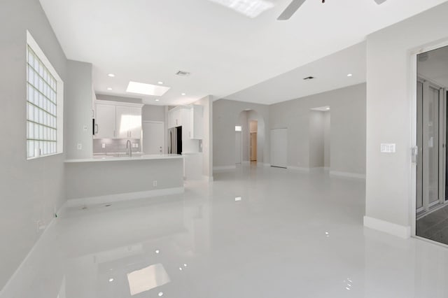 interior space featuring a sink, arched walkways, ceiling fan, and baseboards