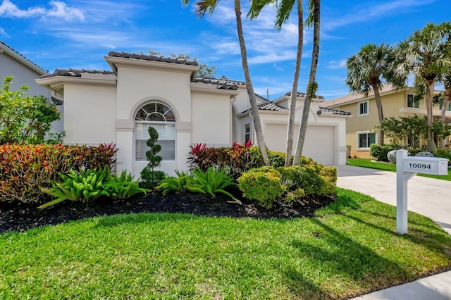 mediterranean / spanish home featuring a garage, a front yard, stucco siding, concrete driveway, and a tile roof