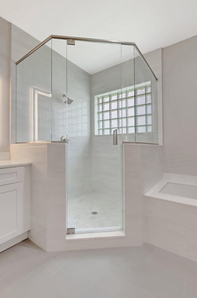 bathroom featuring a bath, a shower stall, tile patterned flooring, and vanity