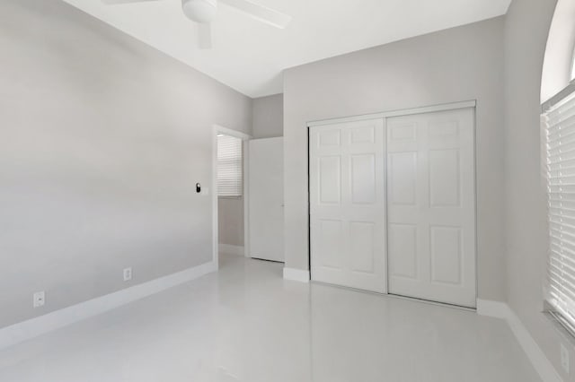 unfurnished bedroom with a ceiling fan, baseboards, concrete flooring, and a closet