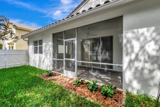 view of home's exterior with a sunroom, fence, stucco siding, and a tile roof