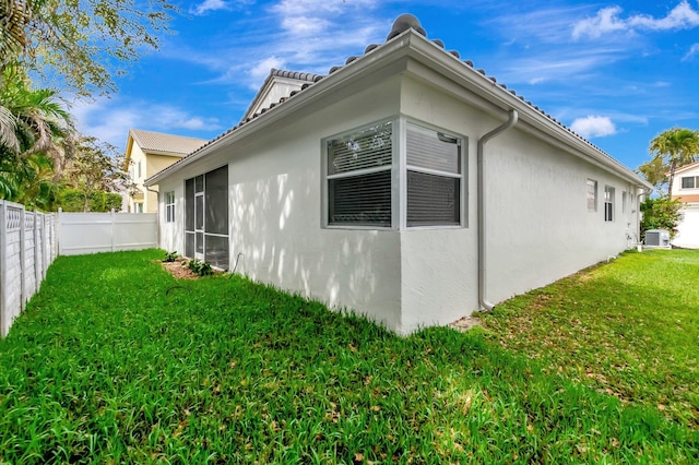 view of home's exterior with a lawn, central AC unit, a fenced backyard, and stucco siding