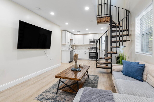 living area with baseboards, stairway, recessed lighting, and light wood finished floors