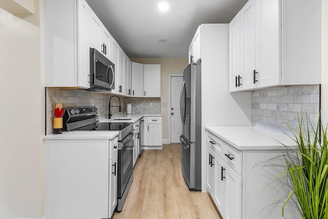 kitchen with white cabinets, light wood finished floors, and appliances with stainless steel finishes