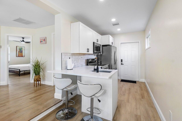 kitchen featuring a breakfast bar area, a sink, visible vents, and stainless steel appliances