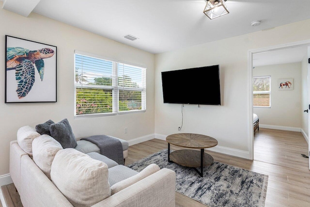 living area featuring visible vents, baseboards, and wood finished floors