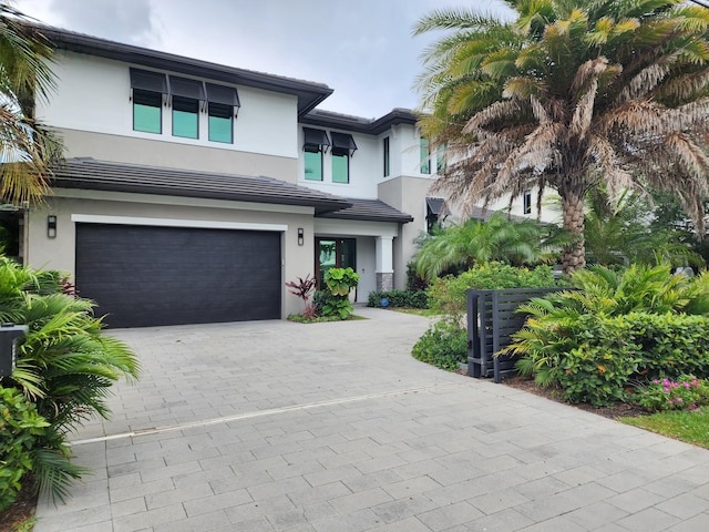 view of front of property with a garage, driveway, stucco siding, and a tile roof