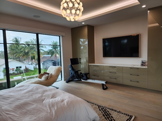 bedroom with a chandelier, recessed lighting, light wood-type flooring, and a raised ceiling