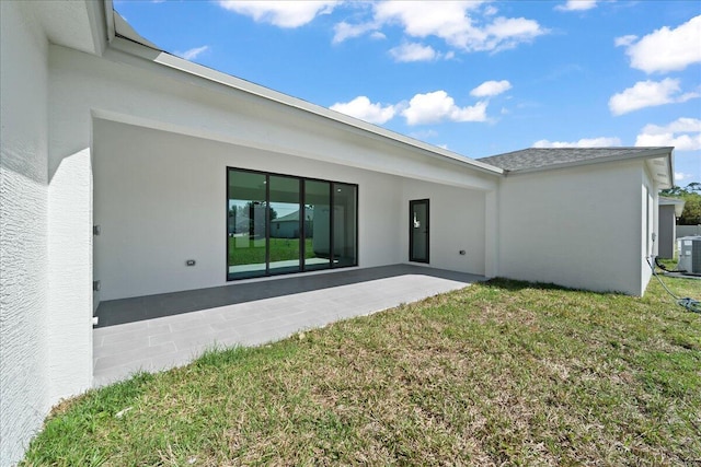back of house with a yard, stucco siding, cooling unit, and a patio area