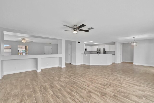 698 SW Mchole Ave, Port Saint Lucie, FL 34953 - unfurnished living room with visible vents, light wood finished floors, and ceiling fan with notable chandelier