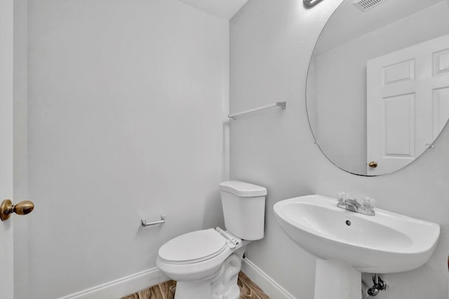 698 SW Mchole Ave, Port Saint Lucie, FL 34953 - half bath with a sink, toilet, wood finished floors, and baseboards