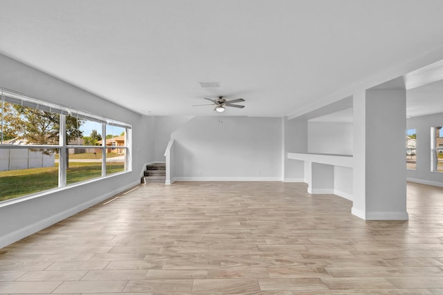 698 SW Mchole Ave, Port Saint Lucie, FL 34953 - unfurnished living room with stairway, a wealth of natural light, a ceiling fan, and light wood-type flooring
