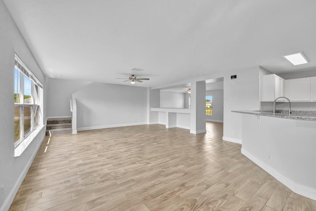 698 SW Mchole Ave, Port Saint Lucie, FL 34953 - unfurnished living room featuring baseboards, a ceiling fan, stairs, and light wood-type flooring