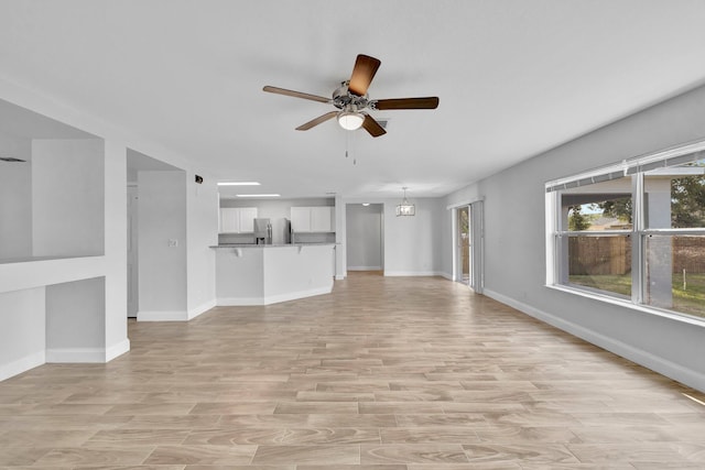 698 SW Mchole Ave, Port Saint Lucie, FL 34953 - unfurnished living room featuring light wood finished floors, a ceiling fan, and baseboards