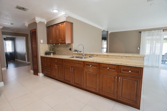 5740 Teakwood Rd, Lake Worth, FL 33467 - kitchen featuring crown molding, a peninsula, visible vents, a sink, and brown cabinets