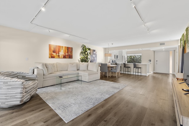 living area with wood finished floors, rail lighting, and visible vents