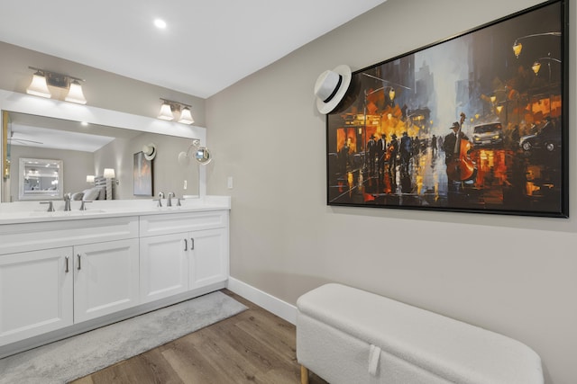bathroom with double vanity, baseboards, a sink, and wood finished floors