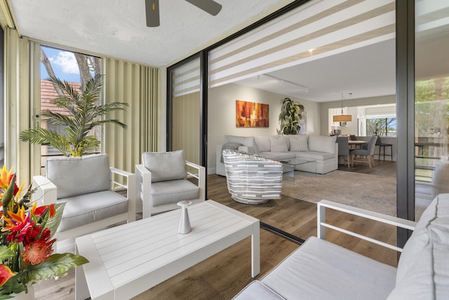 living area with wood finished floors and a ceiling fan