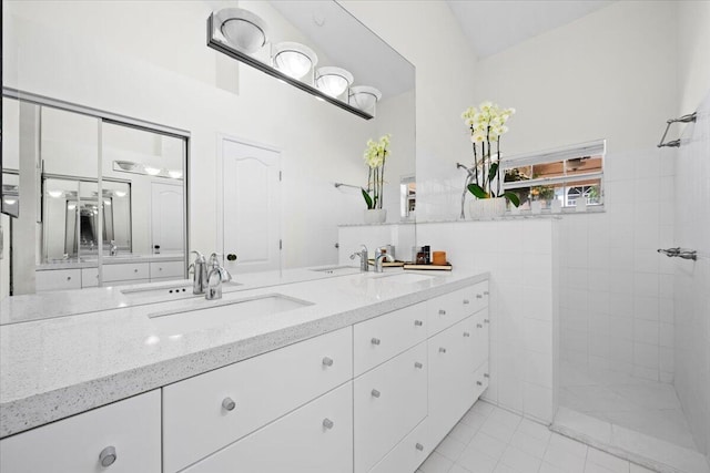 full bath with tile patterned floors, a walk in shower, double vanity, and a sink