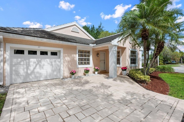 view of front of property featuring a tiled roof, a garage, stucco siding, and driveway