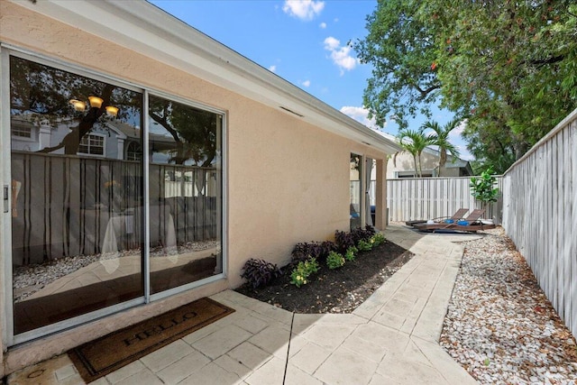 view of side of home featuring a patio, a fenced backyard, and stucco siding