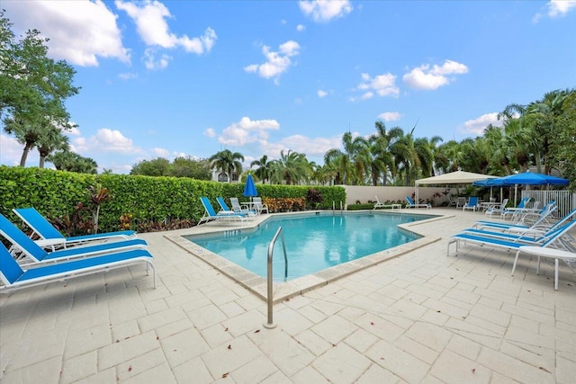 community pool with a patio area and fence