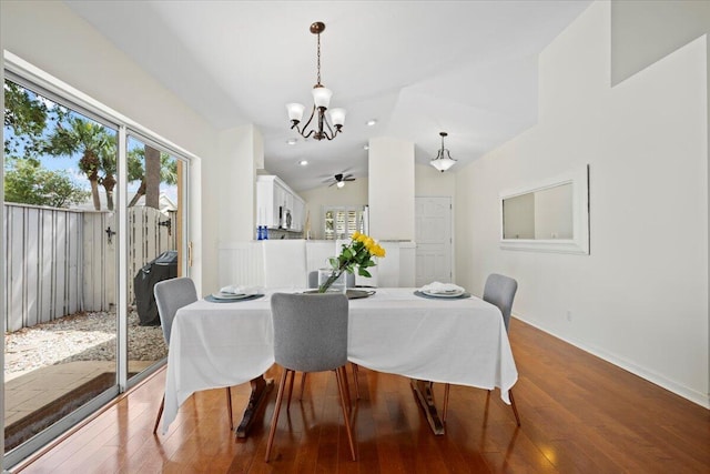 dining space featuring baseboards, hardwood / wood-style flooring, vaulted ceiling, and ceiling fan with notable chandelier