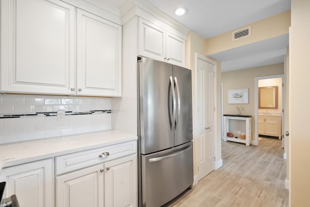 5657 SE Foxcross Pl, Stuart, FL 34997 - kitchen featuring freestanding refrigerator, white cabinetry, backsplash, light wood-type flooring, and light countertops