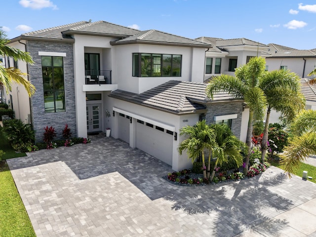 view of front facade with a tile roof, stucco siding, an attached garage, and a balcony