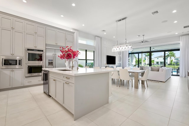 kitchen with open floor plan, built in appliances, visible vents, and plenty of natural light