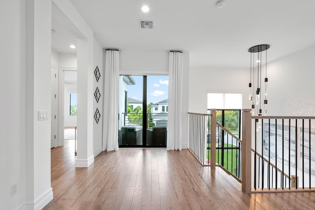 empty room with plenty of natural light, visible vents, and wood finished floors