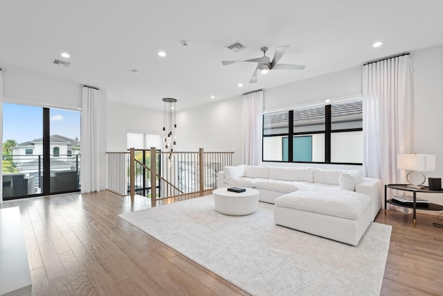 living room featuring light wood finished floors, a ceiling fan, visible vents, and recessed lighting
