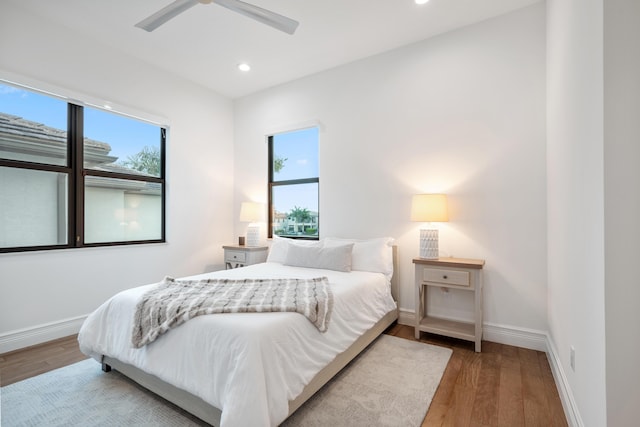 bedroom with wood finished floors, baseboards, multiple windows, and recessed lighting