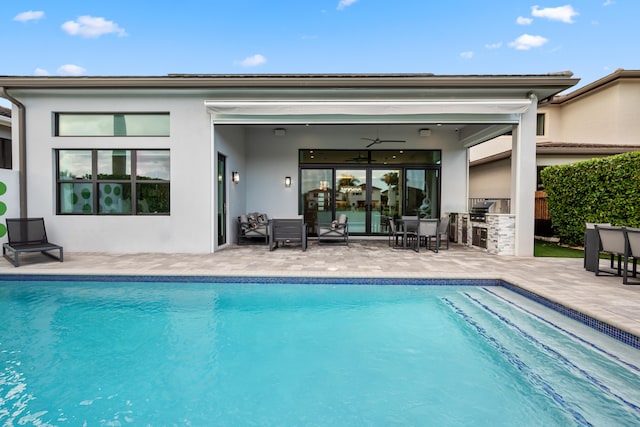 back of house with an outdoor pool, a patio, an outdoor kitchen, and stucco siding