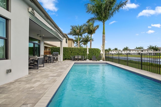 view of swimming pool with an outdoor kitchen, ceiling fan, a fenced backyard, a patio area, and a fenced in pool