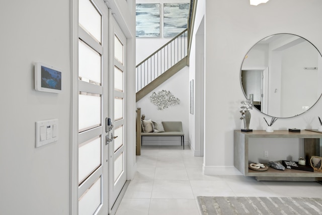 foyer featuring french doors, baseboards, and light tile patterned flooring