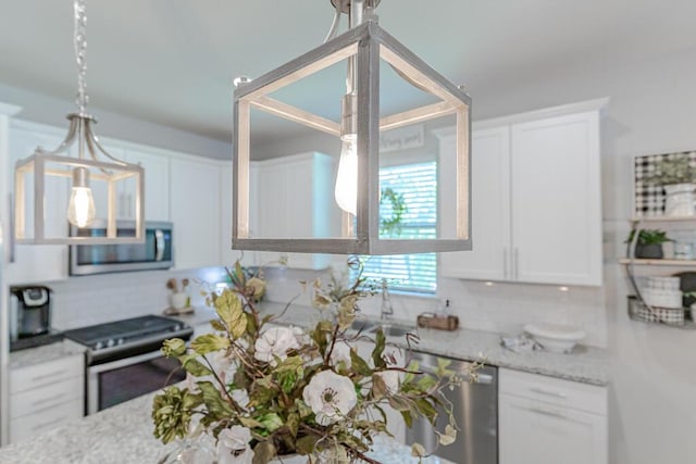 348 SE Courances Dr, Port Saint Lucie, FL 34984 - kitchen featuring appliances with stainless steel finishes, tasteful backsplash, white cabinets, light stone countertops, and pendant lighting