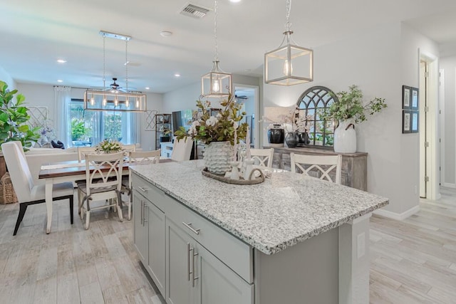 348 SE Courances Dr, Port Saint Lucie, FL 34984 - kitchen featuring a kitchen island, light wood-style floors, light stone countertops, decorative light fixtures, and recessed lighting