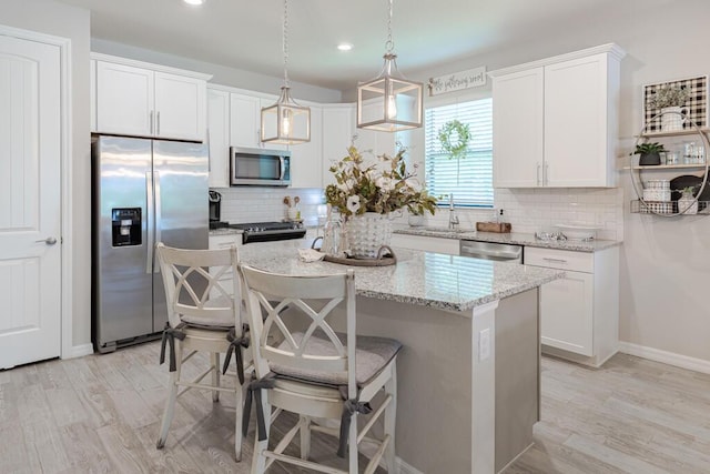348 SE Courances Dr, Port Saint Lucie, FL 34984 - kitchen with appliances with stainless steel finishes, decorative backsplash, a center island, a kitchen bar, and white cabinets
