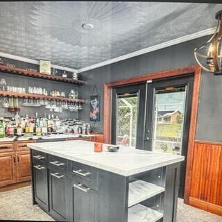 bar featuring indoor bar, ornamental molding, wainscoting, and wooden walls