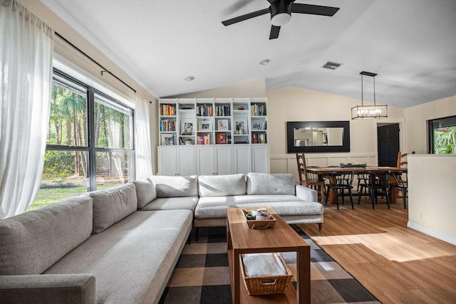 18292 126th Ter N, Jupiter, FL 33478 - living room with vaulted ceiling, wood finished floors, a ceiling fan, wainscoting, and a chandelier