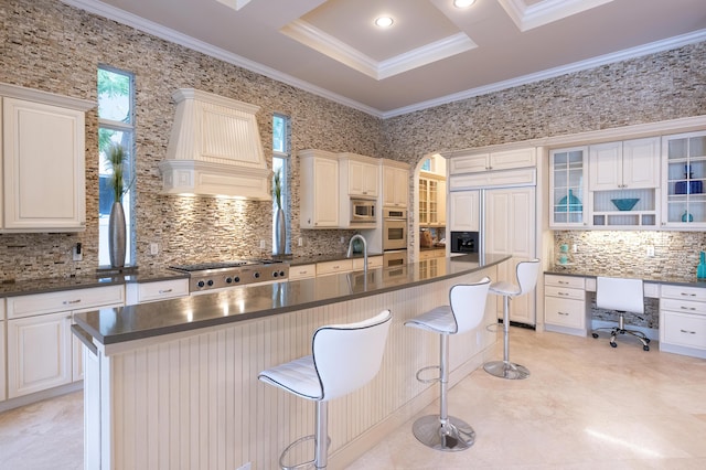 kitchen with premium range hood, crown molding, built in appliances, and dark countertops