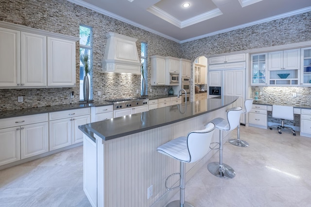 kitchen featuring stainless steel appliances, custom range hood, crown molding, and dark countertops