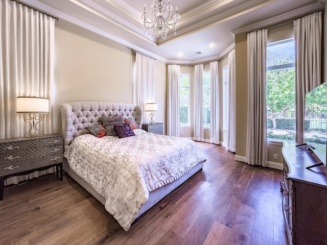 bedroom with a chandelier, dark wood-style flooring, a tray ceiling, and multiple windows