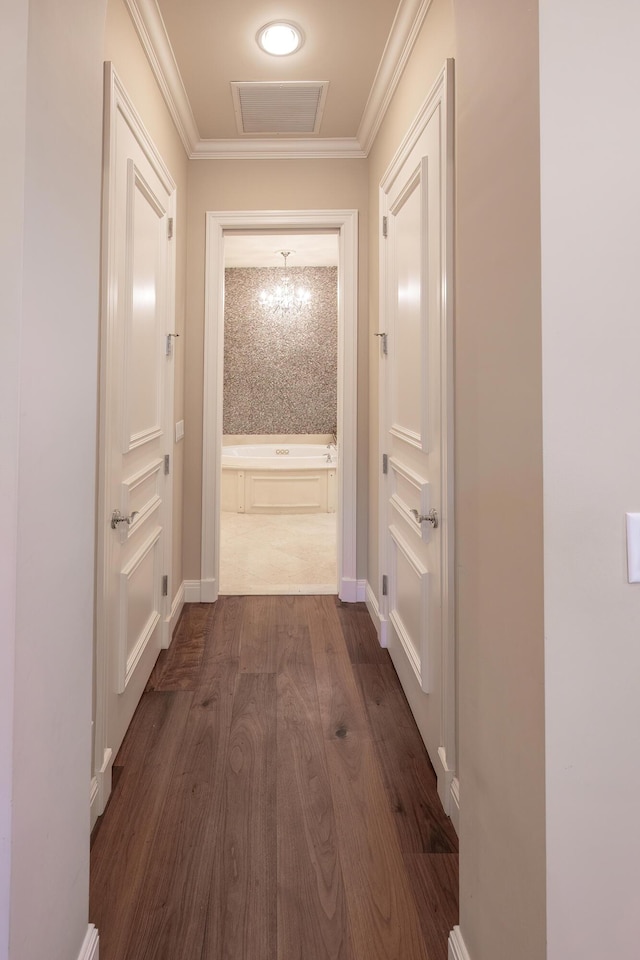 corridor featuring crown molding, visible vents, baseboards, and dark wood finished floors