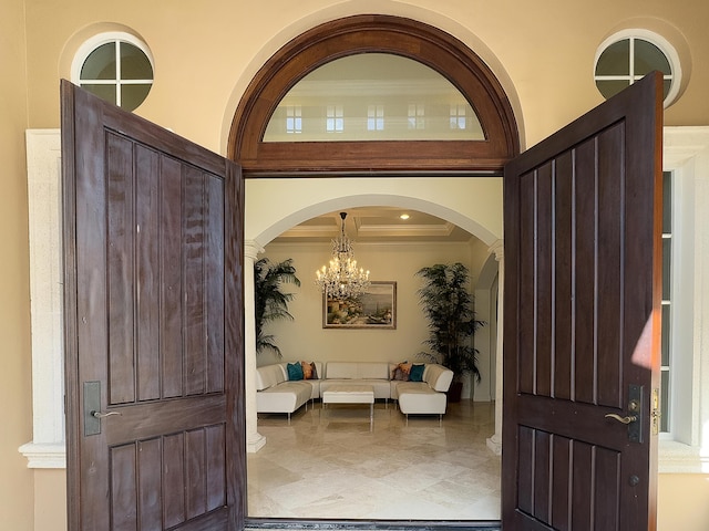 foyer featuring ornamental molding, arched walkways, and an inviting chandelier
