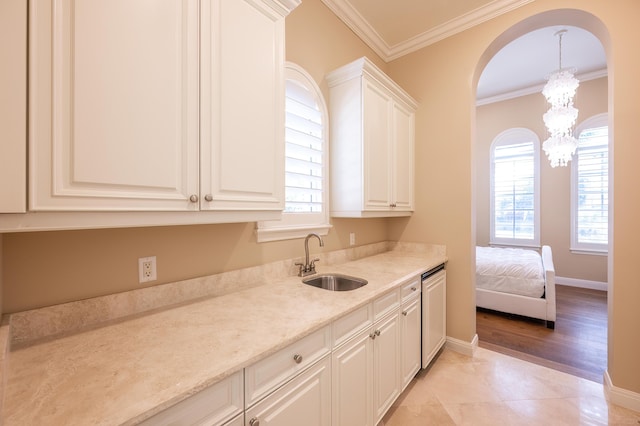 kitchen with crown molding, arched walkways, dishwasher, a sink, and a notable chandelier