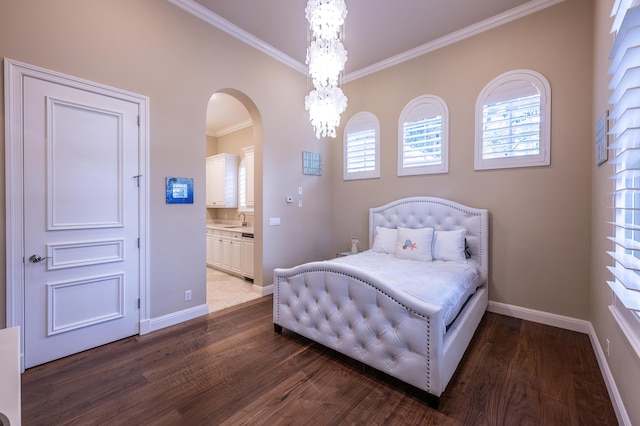 bedroom with baseboards, ornamental molding, connected bathroom, arched walkways, and wood finished floors